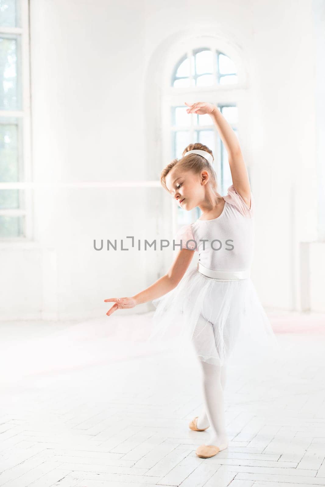 Little ballerina girl in a tutu. Adorable child dancing classical ballet in a white studio. Children dance. Kids performing. Young gifted dancer in a class. Preschool kid taking art lessons.