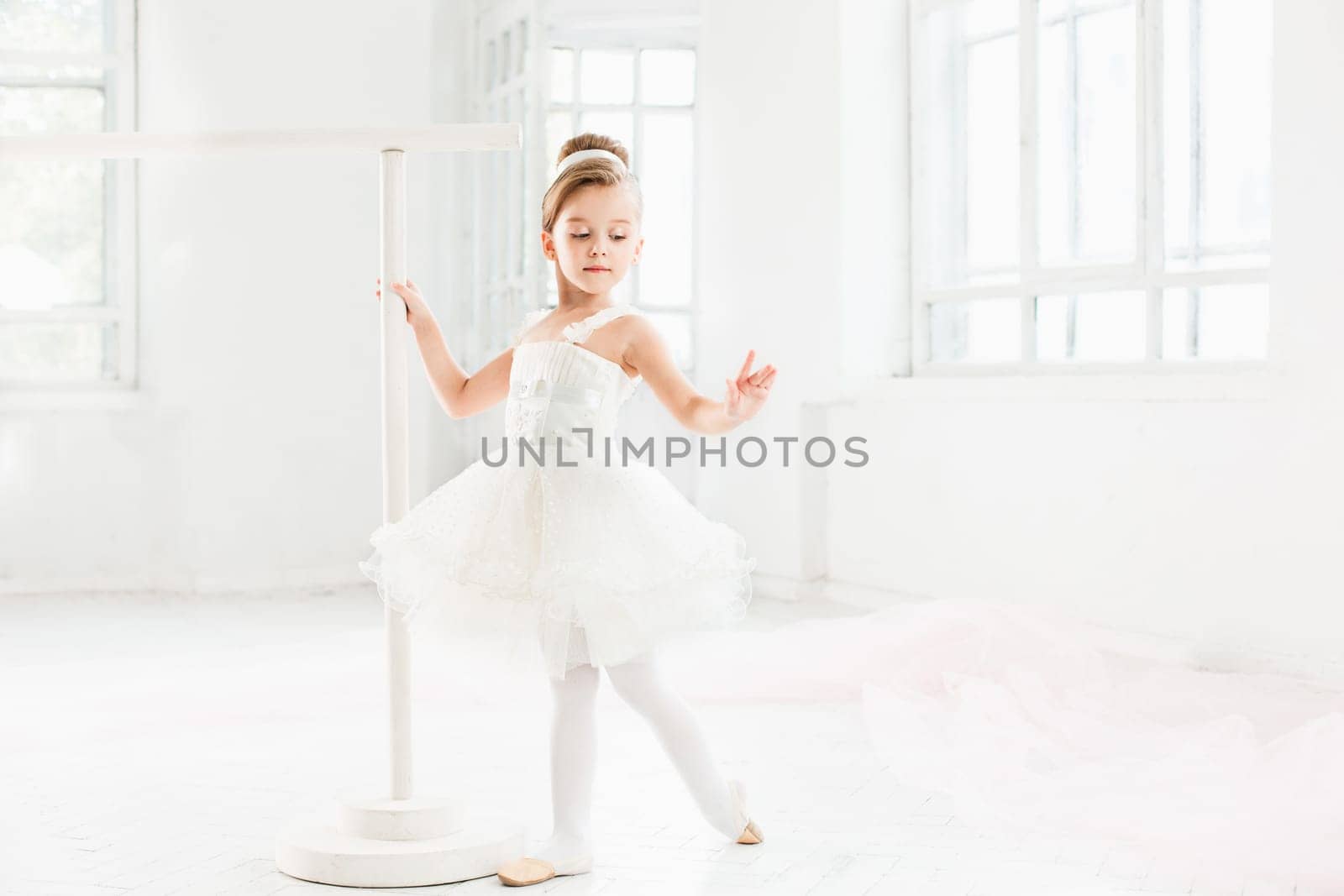 Little ballerina girl in a tutu. Adorable child dancing classical ballet in a white studio. Children dance. Kids performing. Young gifted dancer in a class. Preschool kid taking art lessons.
