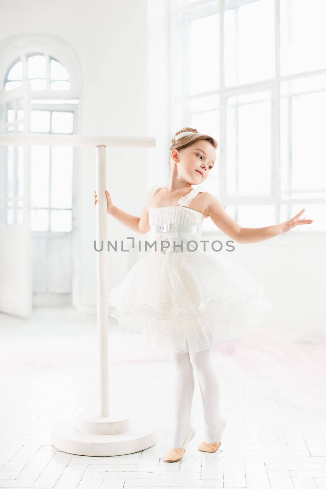 Little ballerina girl in a tutu. Adorable child dancing classical ballet in a white studio. Children dance. Kids performing. Young gifted dancer in a class. Preschool kid taking art lessons.