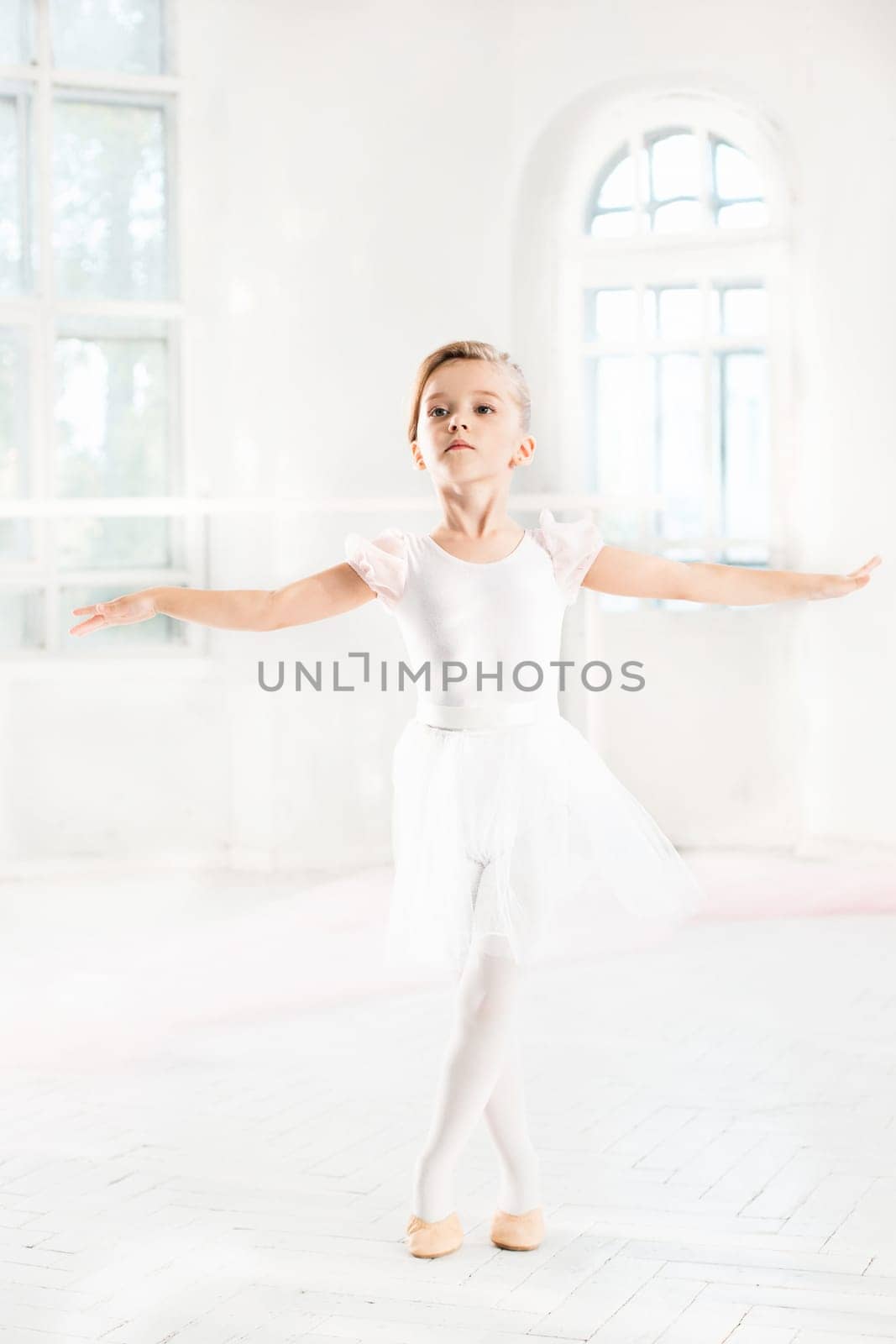 Little ballerina girl in a tutu. Adorable child dancing classical ballet in a white studio. Children dance. Kids performing. Young gifted dancer in a class. Preschool kid taking art lessons.