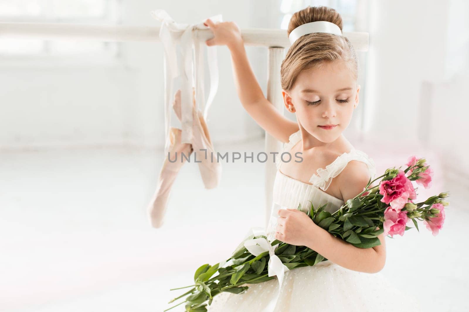 Little ballerina girl in a tutu. Adorable child dancing classical ballet in a white studio. Children dance. Kids performing. Young gifted dancer in a class. Preschool kid taking art lessons.