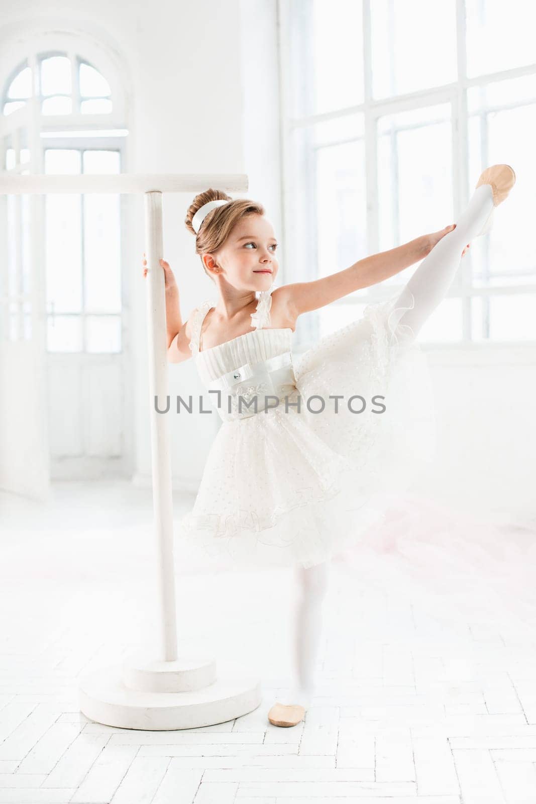 Little ballerina girl in a tutu. Adorable child dancing classical ballet in a white studio. Children dance. Kids performing. Young gifted dancer in a class. Preschool kid taking art lessons.