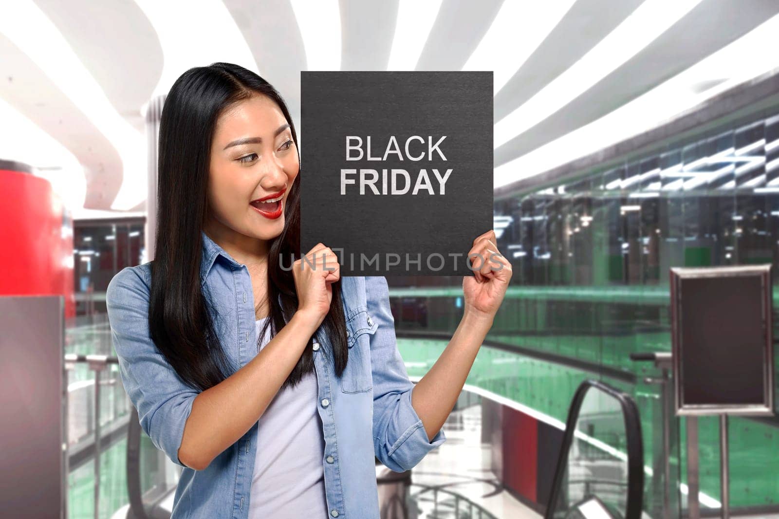 Young asian woman holding sign board with Black Friday text on the mall
