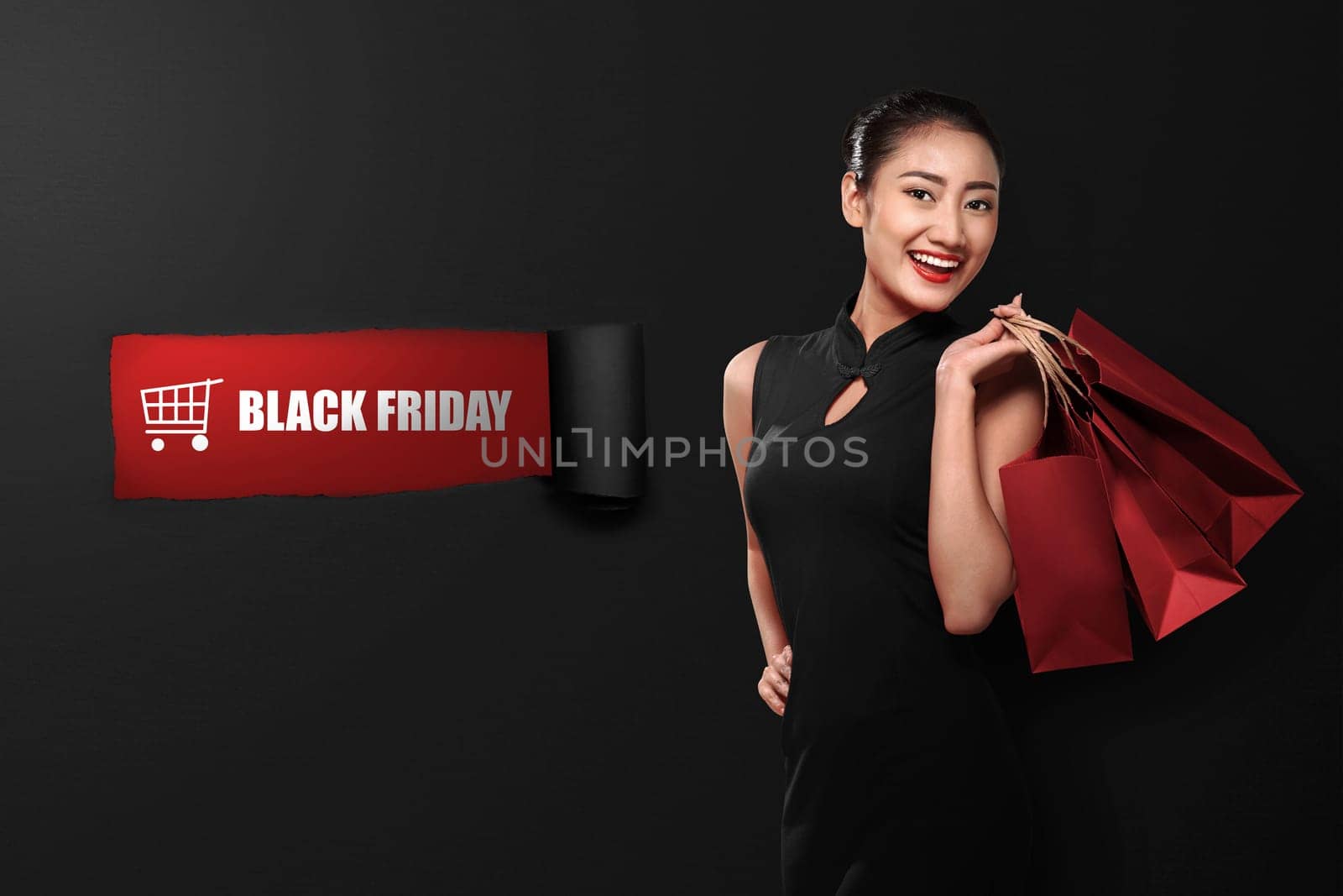 Happy asian woman holding paperbag with Black Friday text on ripped paper