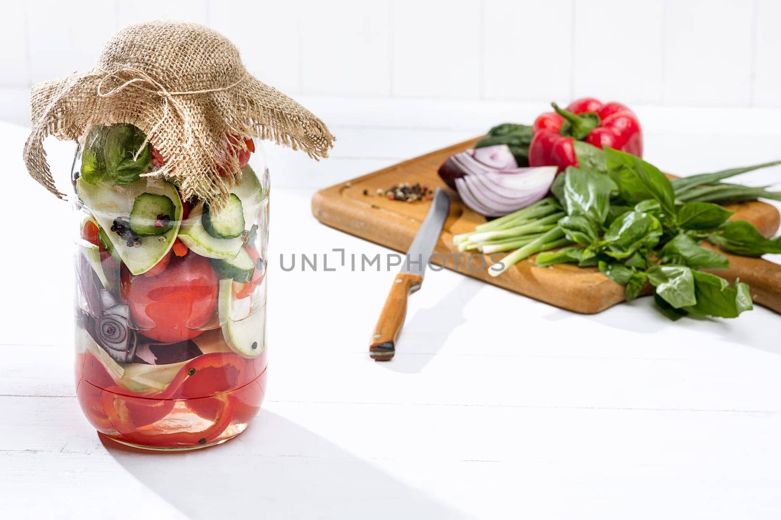 Canned tomatoes and fresh tomatos and other cut vegetables on white background
