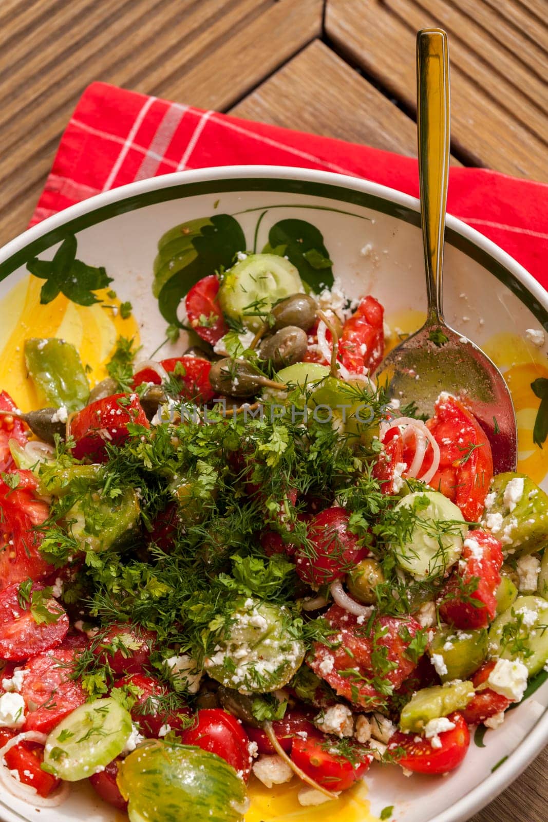 Bowl of marinated Greek salad with tomato cheese and olives on a wood edible