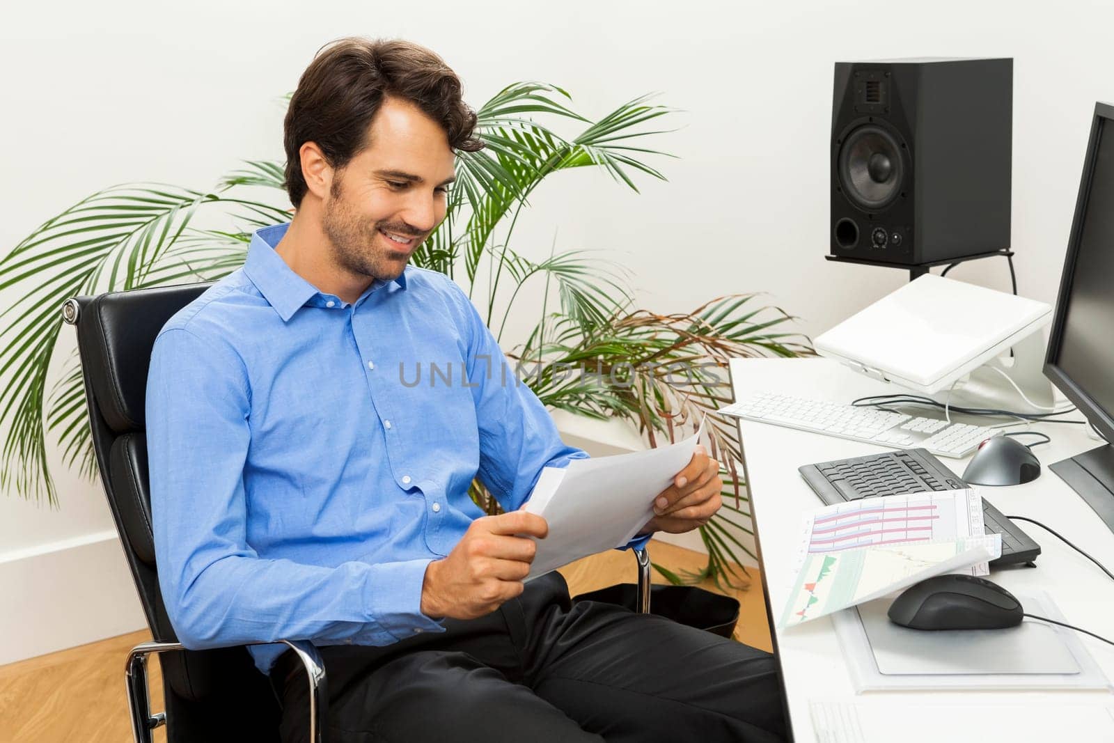 Young businessman sits with documents at a grater table in the office and informs himself