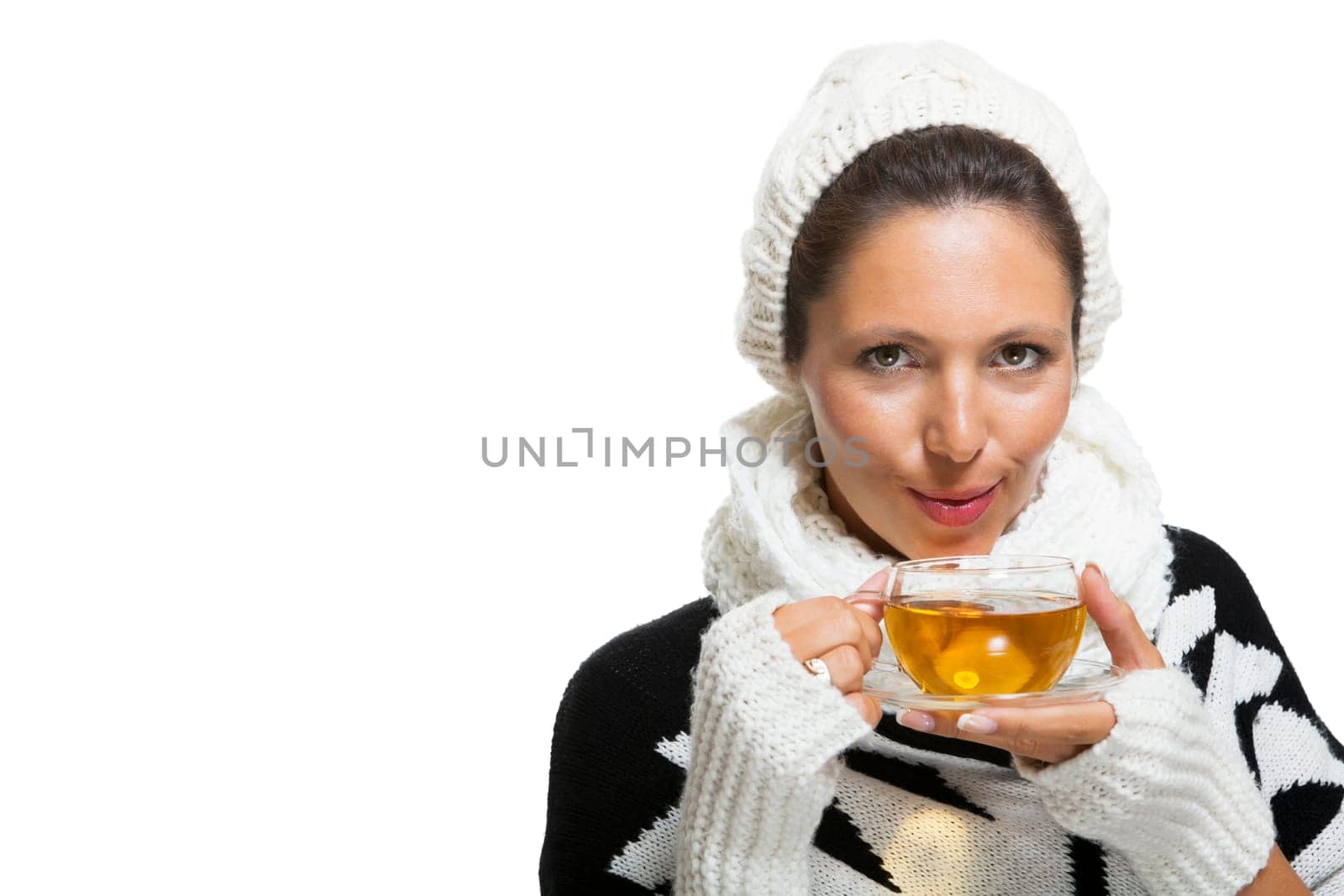 Young brunette woman with white wool lyane drinks a cup of tea to warm up isolated on white background