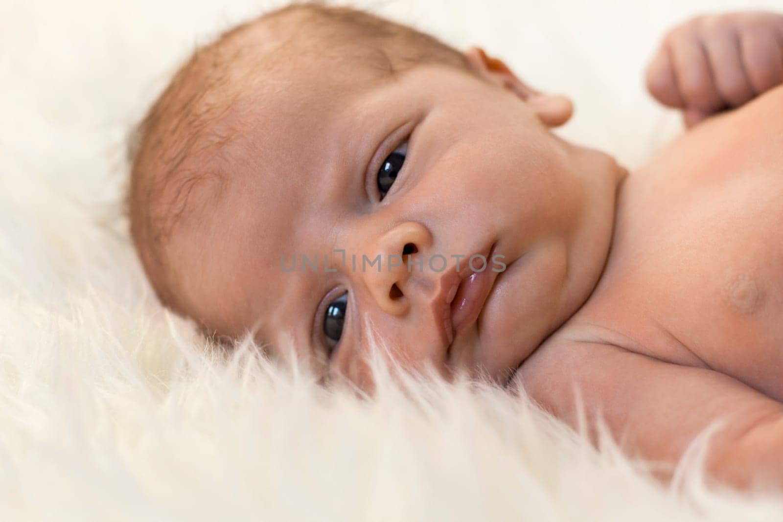 Close-up of a newborn baby lying on a fluffy white blanket