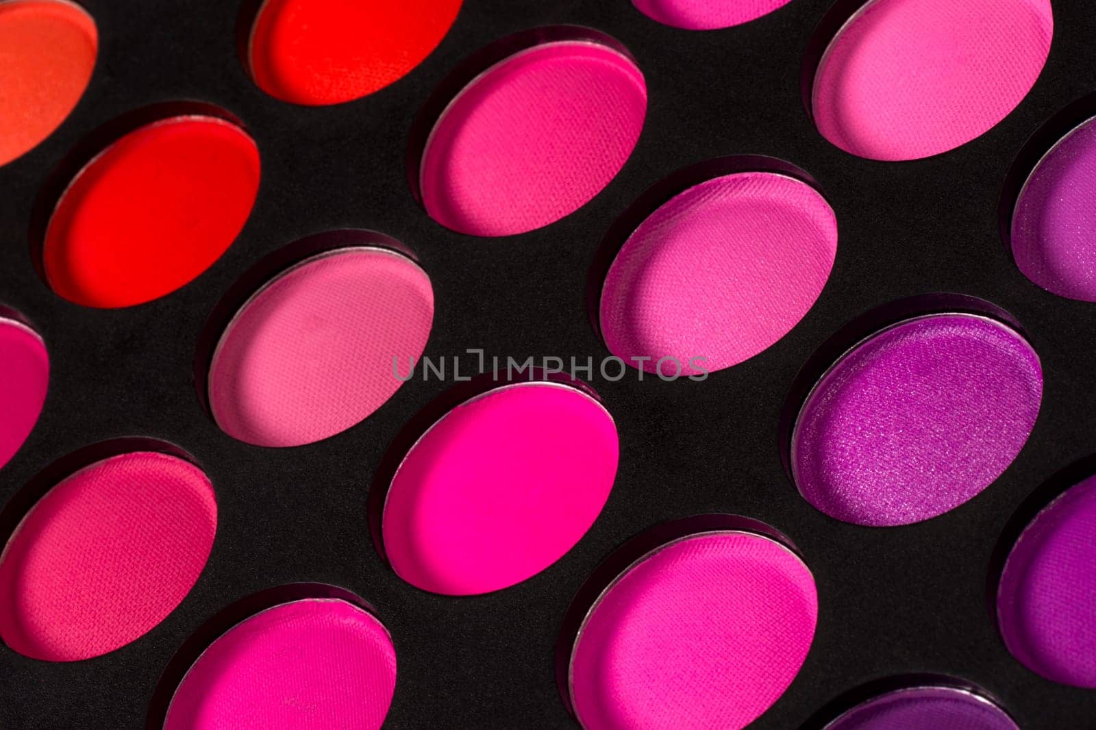 Eye shadow palette with pink colors on black background.