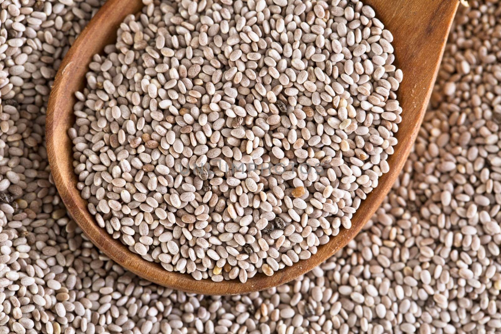 Close up of white chia seeds in wooden spoon.