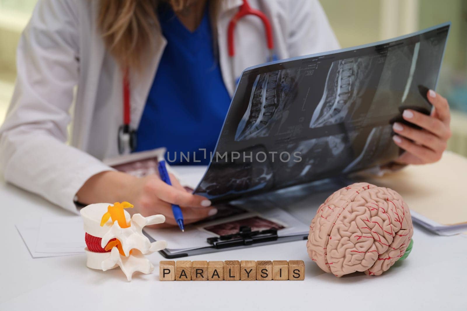 A skilled medical professional is reviewing Xrays and models related to paralysis treatment and care