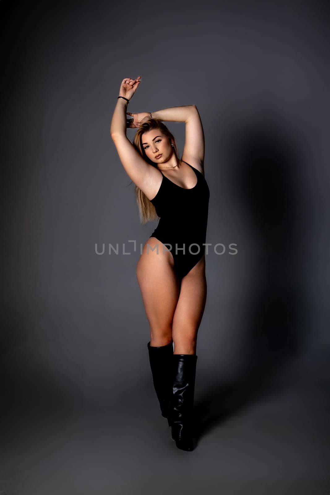 A professional dancer strikes a graceful pose in a black bodysuit, showcasing strength and elegance.