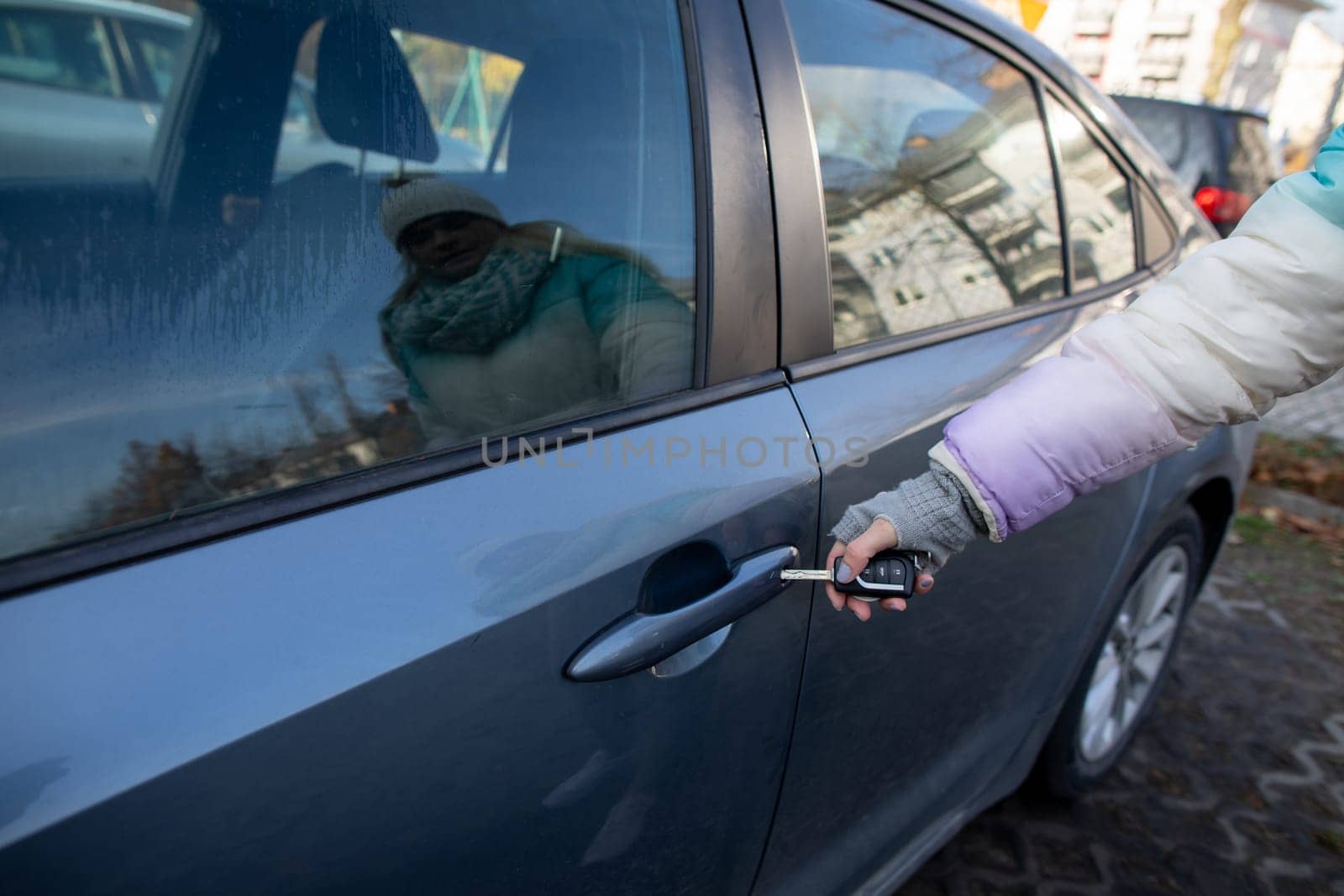 A person happily unlocking their car door with a key fob on a bright and sunny day outside in the open air