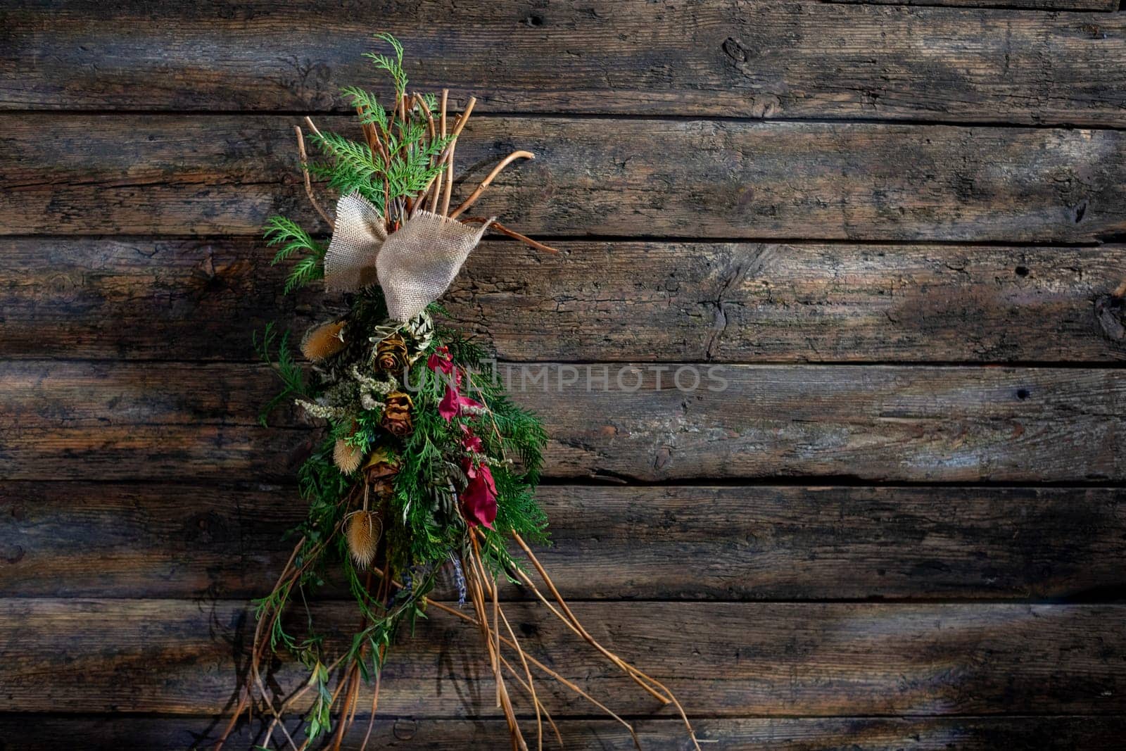 A beautiful rustic decoration featuring natural greens, berries, and twigs against a wooden background.