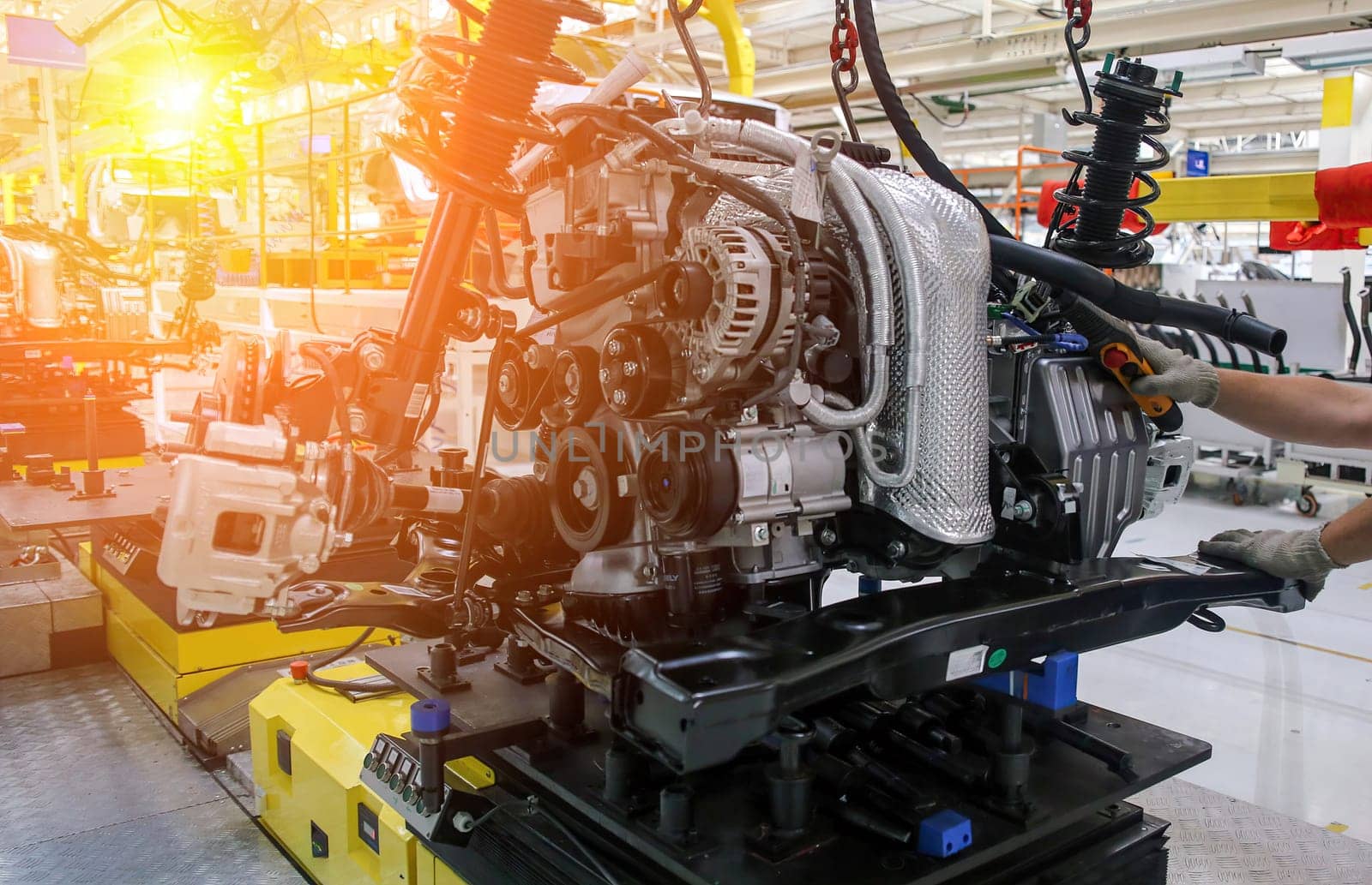 Workers are assembling an automotive engine on a conveyor system in a well-lit factory, focusing on precision and efficiency.