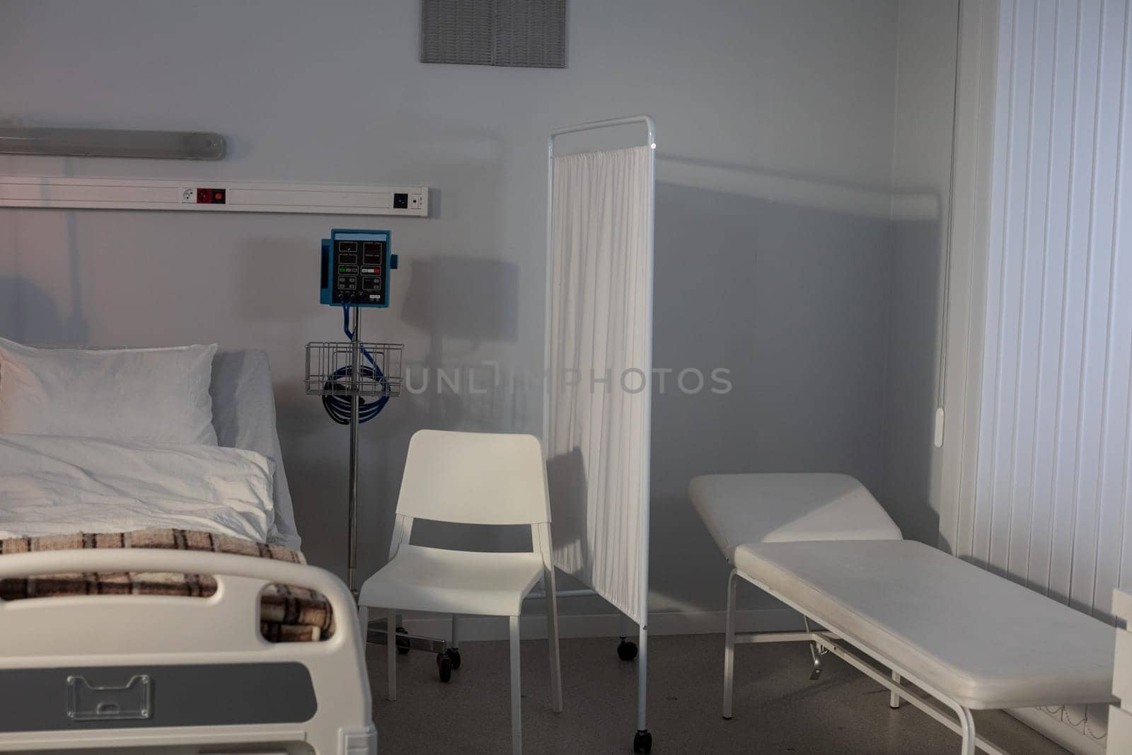 A meticulously sterile hospital room that includes a patient bed, necessary medical equipment, and seating areas