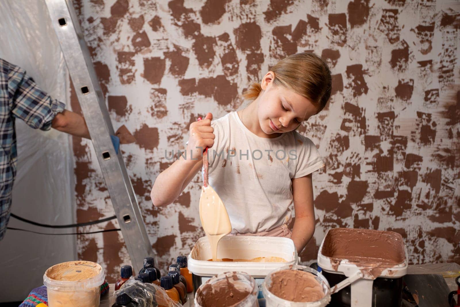 A young girl joyfully painting a colorful wall while actively engaged in an exciting home renovation project