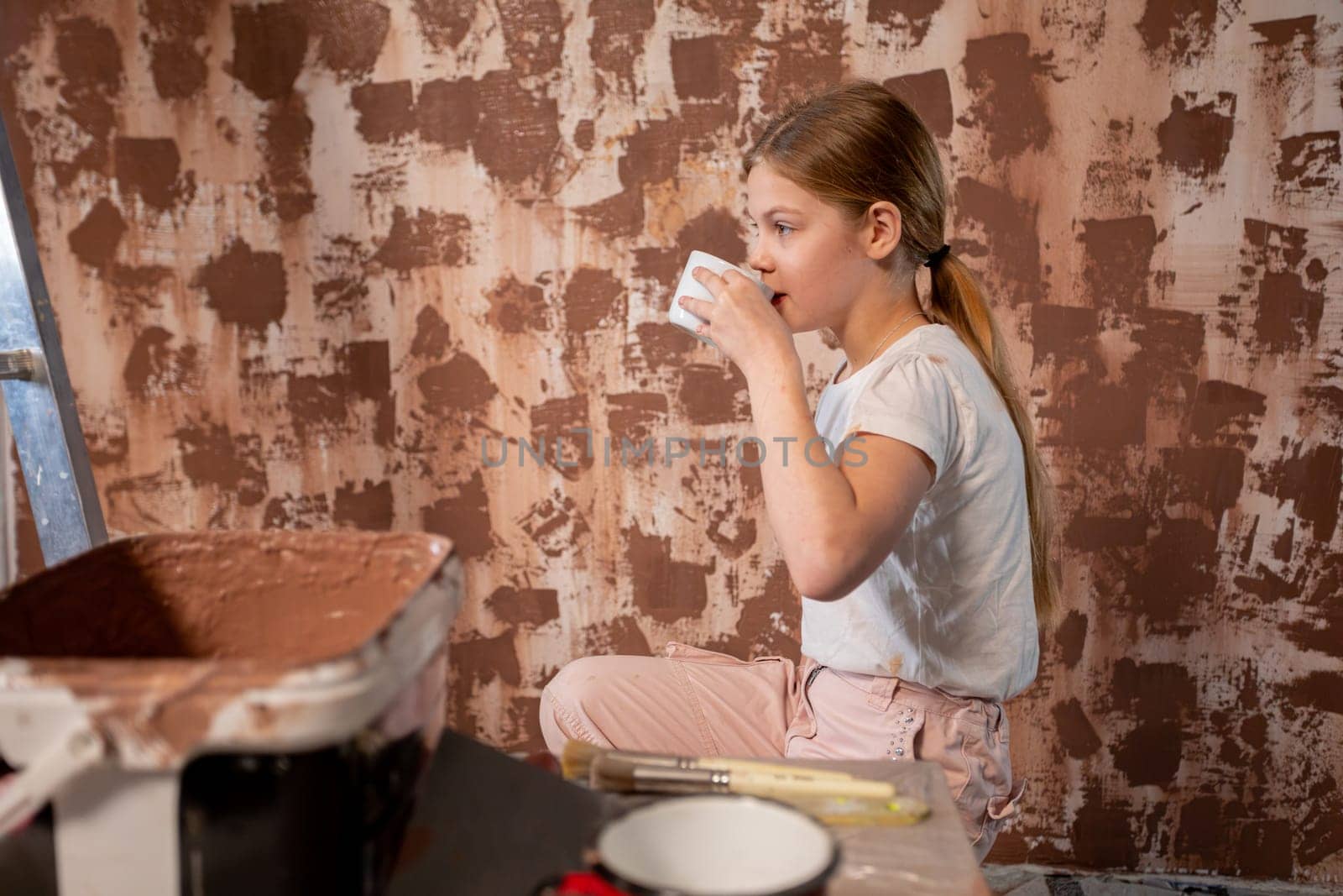 A cheerful girl sips a colorful drink while engaged in a home project, showcasing her creativity and spirit