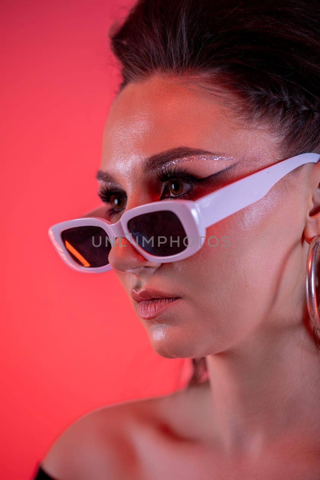 An eyecatching and striking portrait of a stylish woman donning trendy sunglasses set against a vibrant background