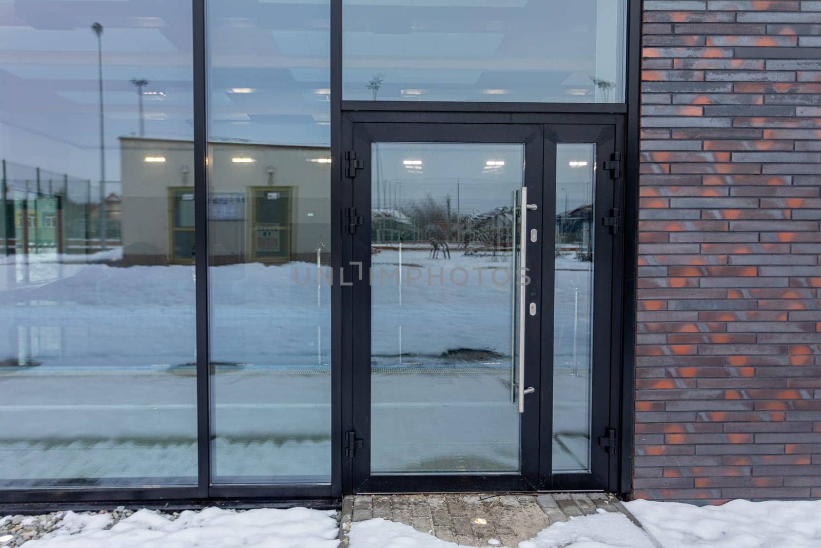 A contemporary glass door entrance beautifully set against a snowy backdrop, creating a striking visual scene