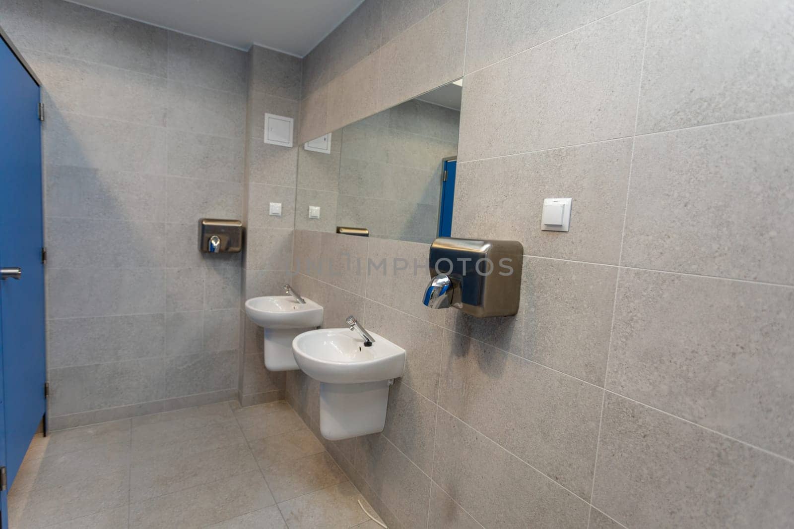 This contemporary bathroom features dual basins and efficient hand drying facilities for user convenience