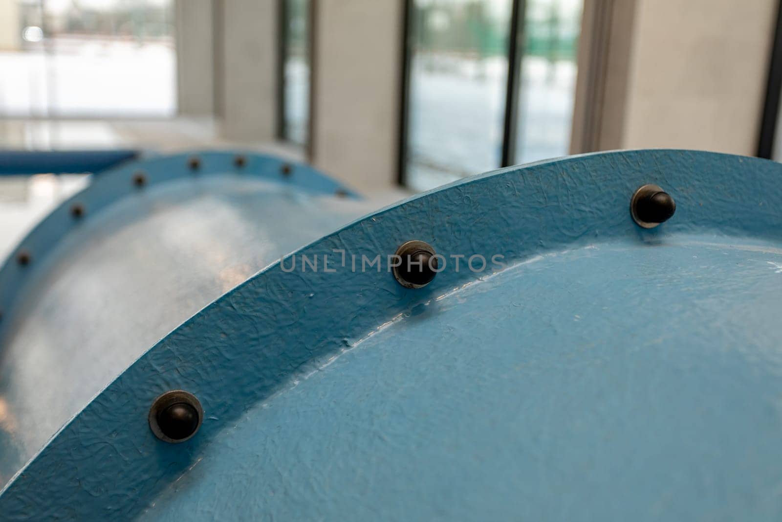 This is a detailed view of a blue industrial pipe, highlighting the fasteners and the unusually smooth surface