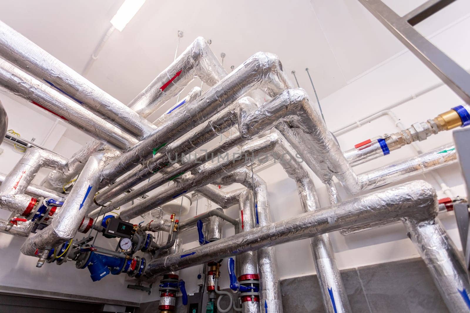 A complex and intricate arrangement of numerous metallic pipes and valves situated within an industrial setting