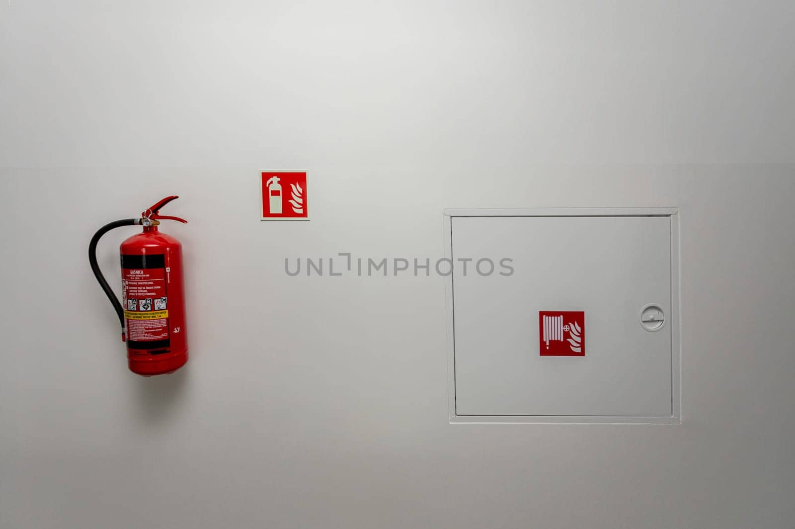 A fire extinguisher and emergency exit signage on a wall, highlighting fire safety in public spaces.
