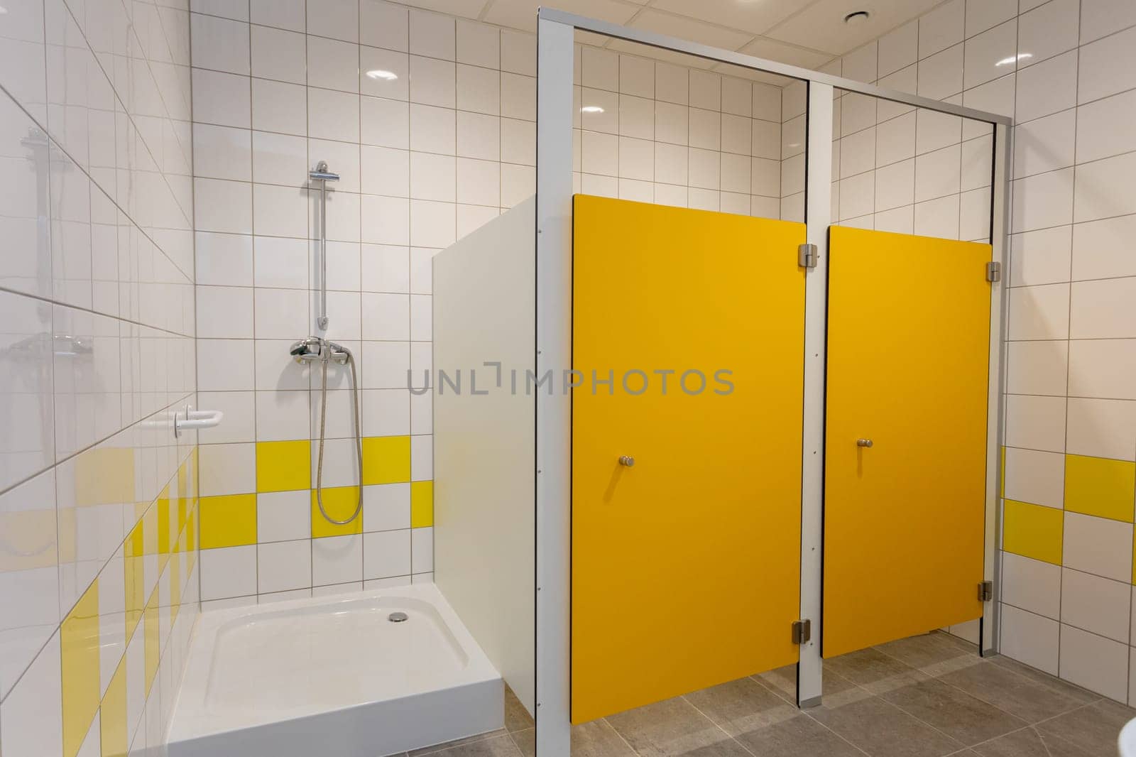 This modern bathroom features a contemporary shower space adorned with vibrant yellow accents and elegant tiled walls