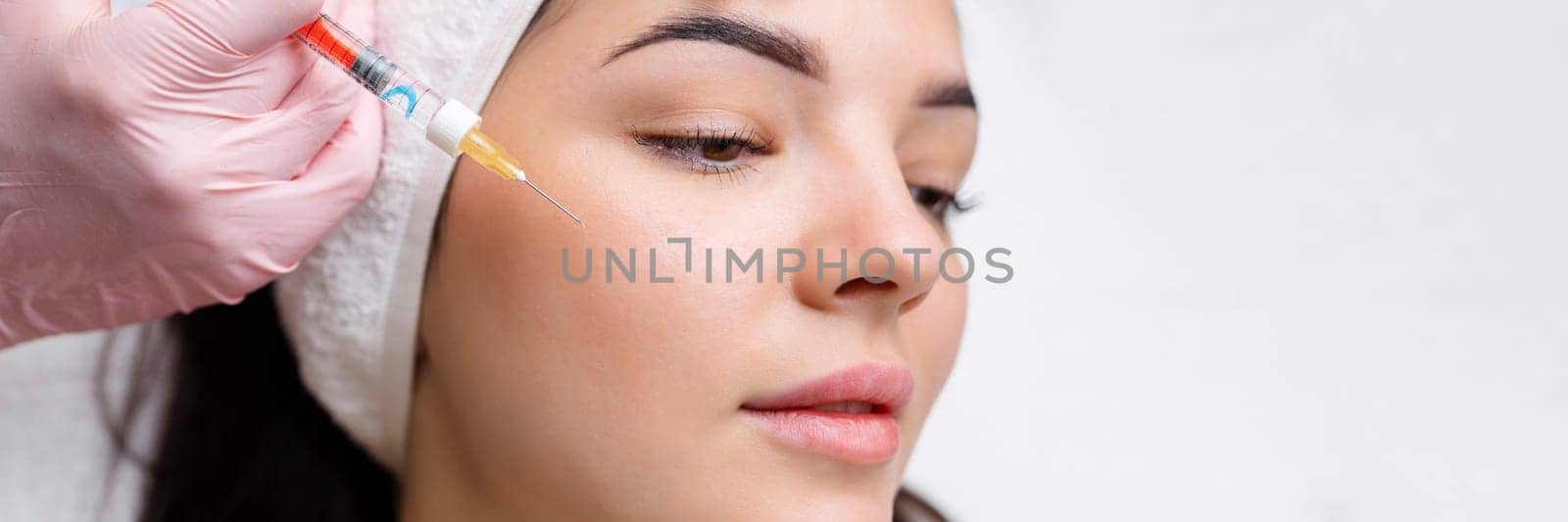 Cosmetologist makes rejuvenating anti wrinkle injections on the face of a beautiful woman. Female aesthetic cosmetology in a beauty salon
