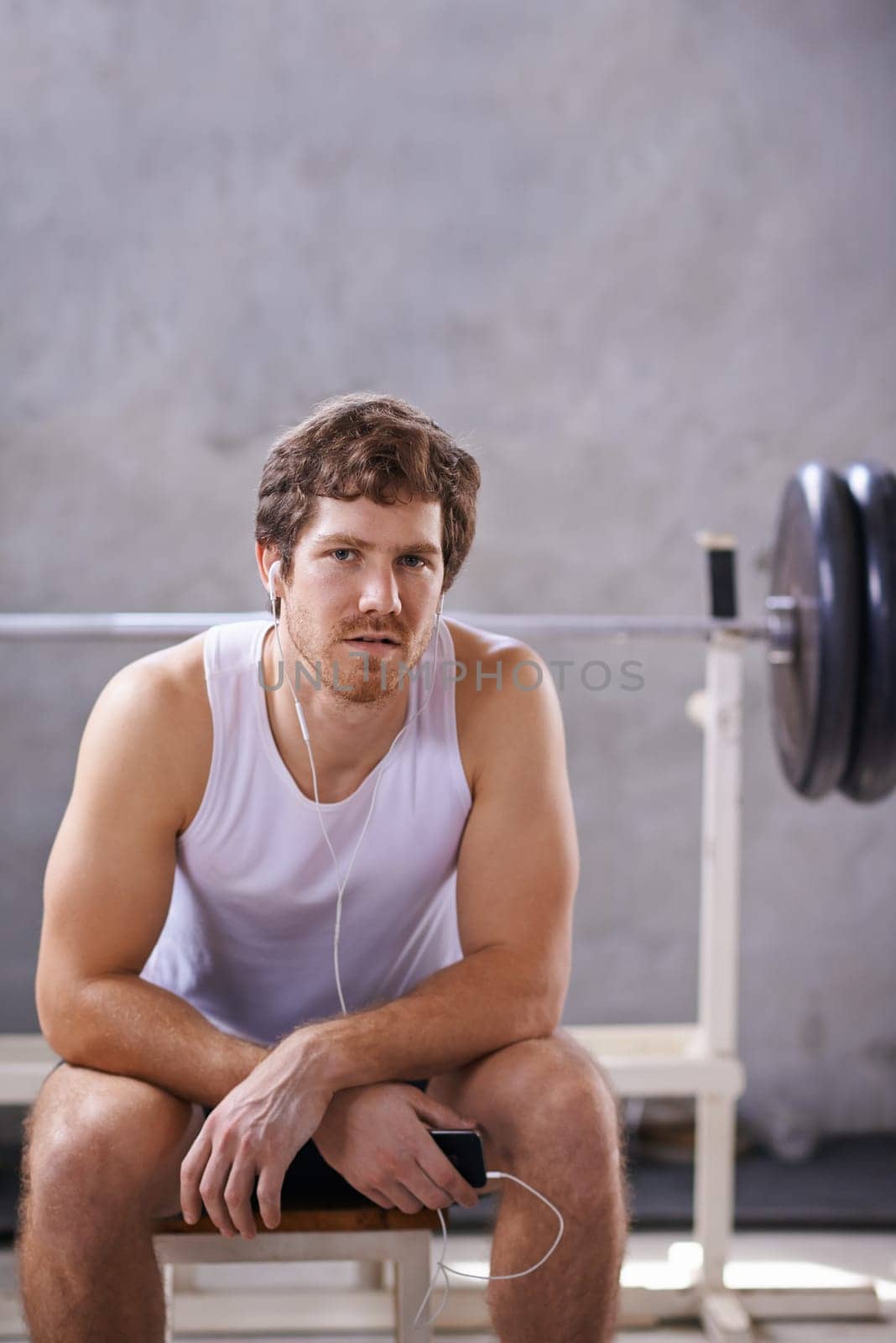 Young man with earphones sitting his private gym ready for a session