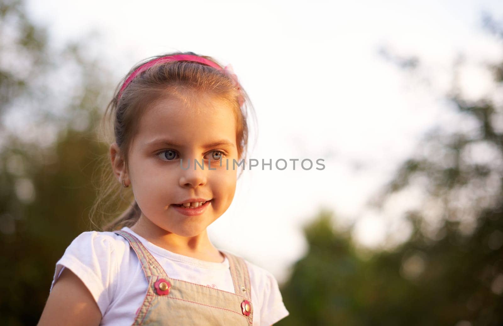 Portrait of a beautiful little girl looking thoughtful in the light of a late afternoon sun