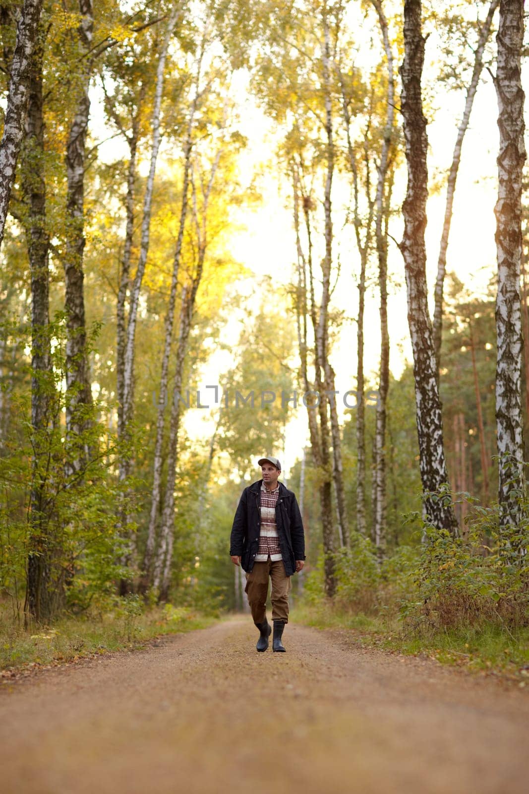 Young man walking along a dirt road in a forest early in the morning