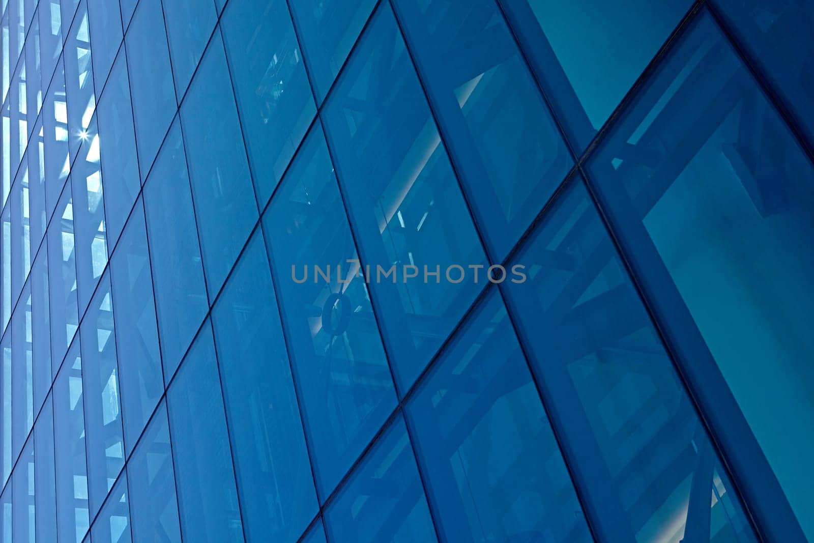 Abstract image of the facade of a modern high rise building covered in reflective plate glass