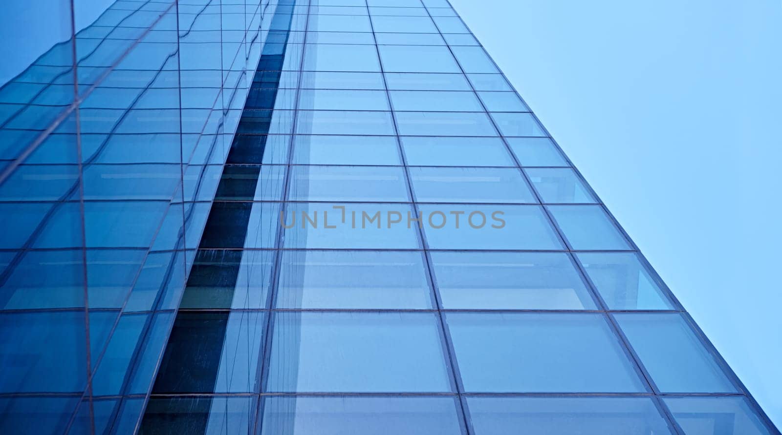 Abstract closeup of the glass-clad facade of a modern building covered in reflective plate glass