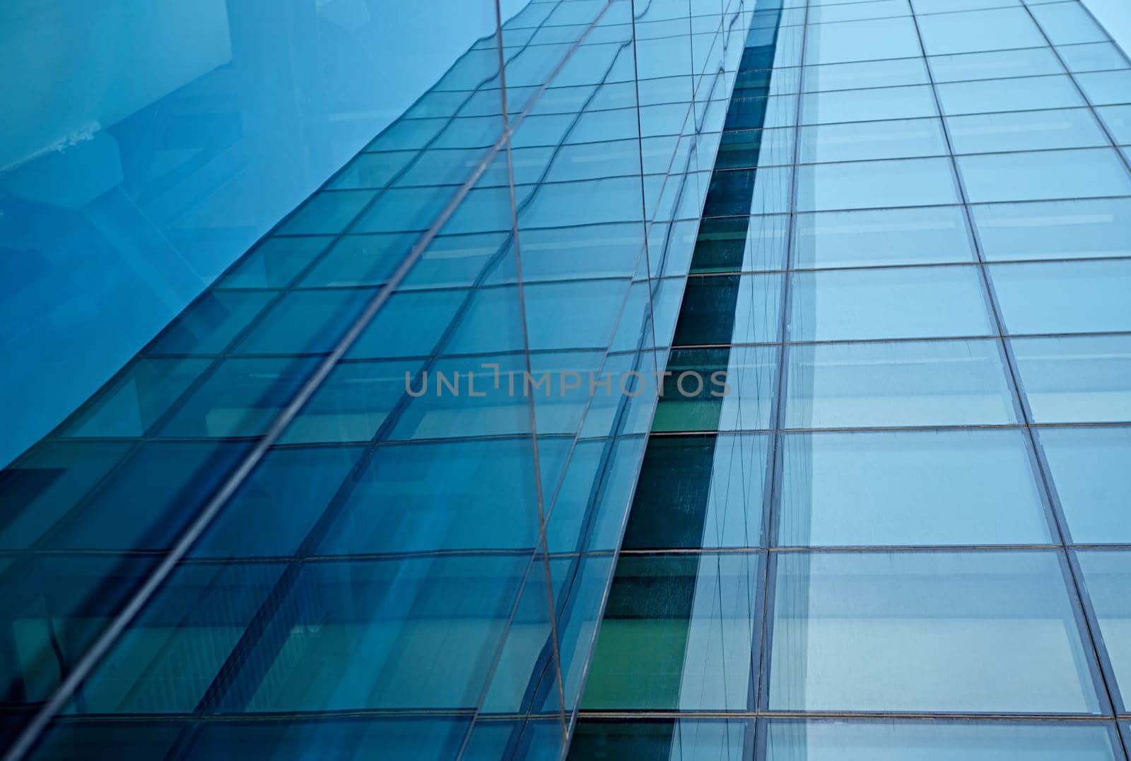 Abstract closeup of the glass-clad facade of a modern building covered in reflective plate glass