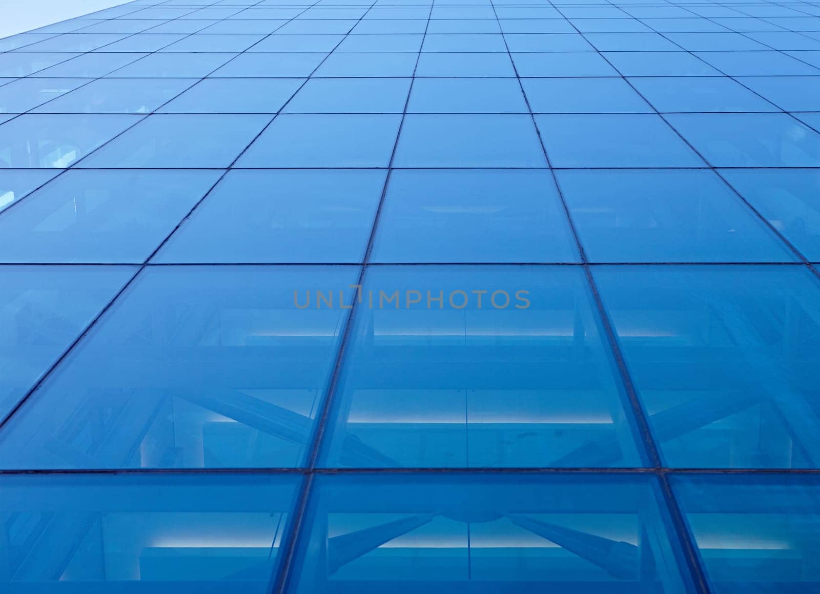 Abstract closeup of the glass-clad facade of a modern building covered in reflective plate glass