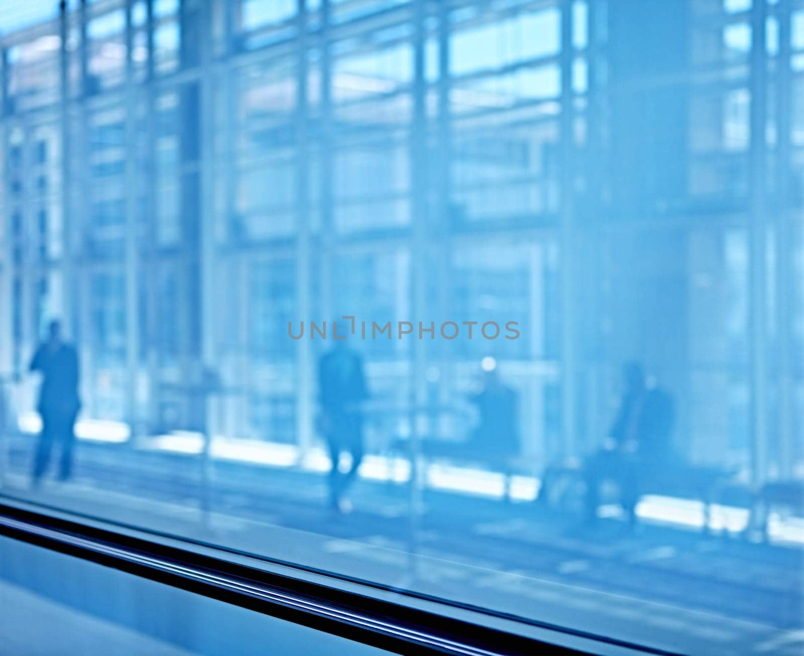 Blue tone images of real businesspeople in motion through glass in a busy conference centre
