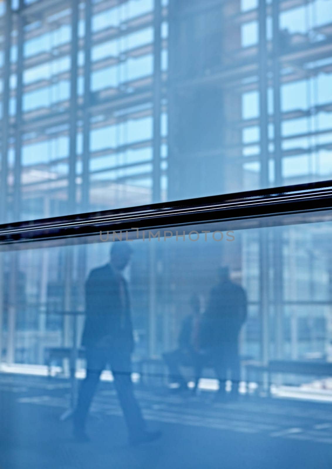 Blue tone images of real businesspeople in motion through glass in a busy conference centre