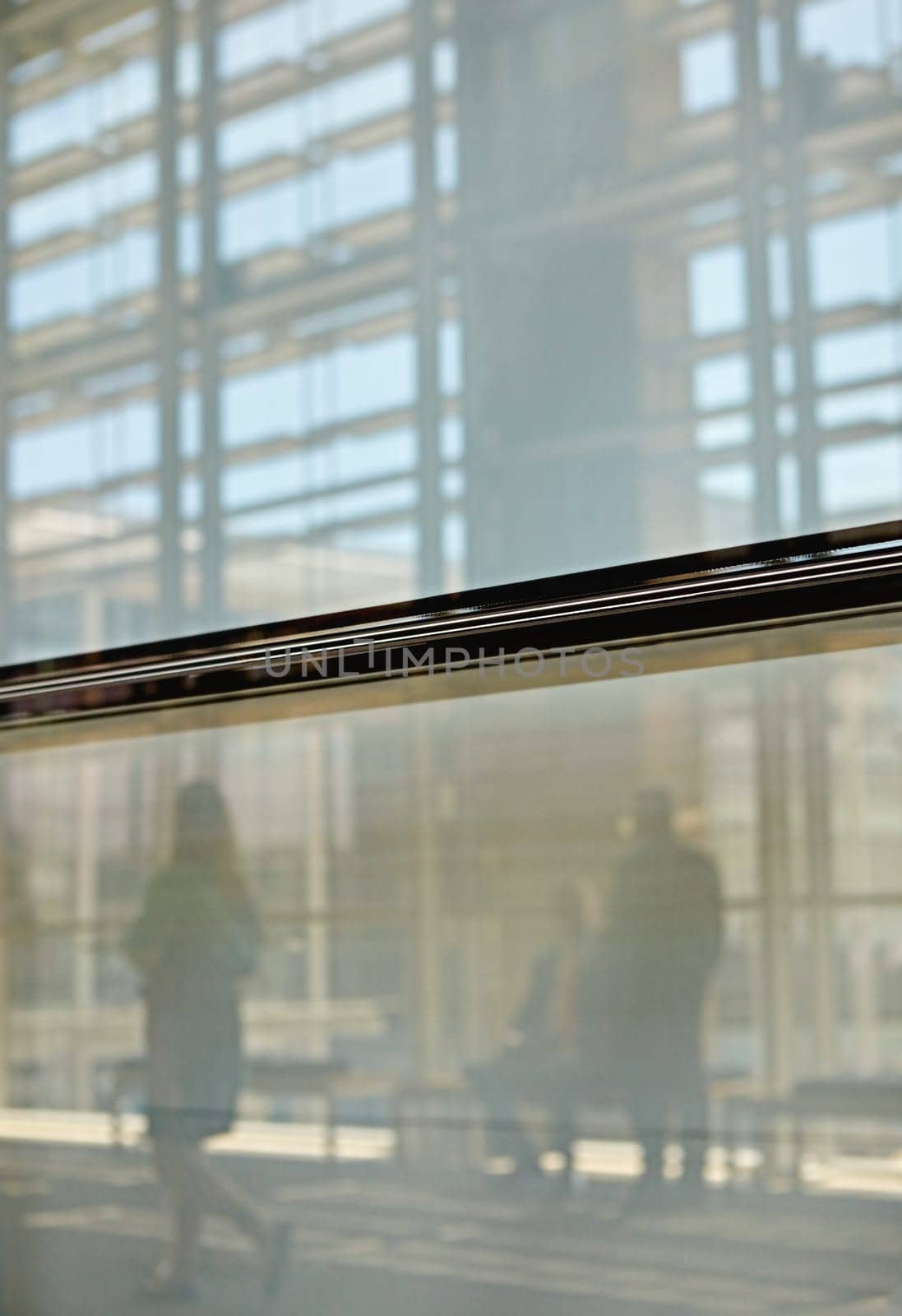 Abstract images of real businesspeople in motion through glass in a busy conference centre