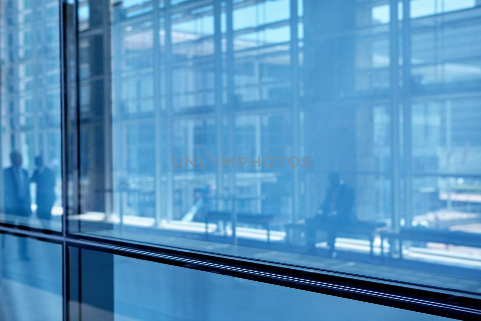 Blue tone images of real businesspeople in motion through glass in a busy conference centre