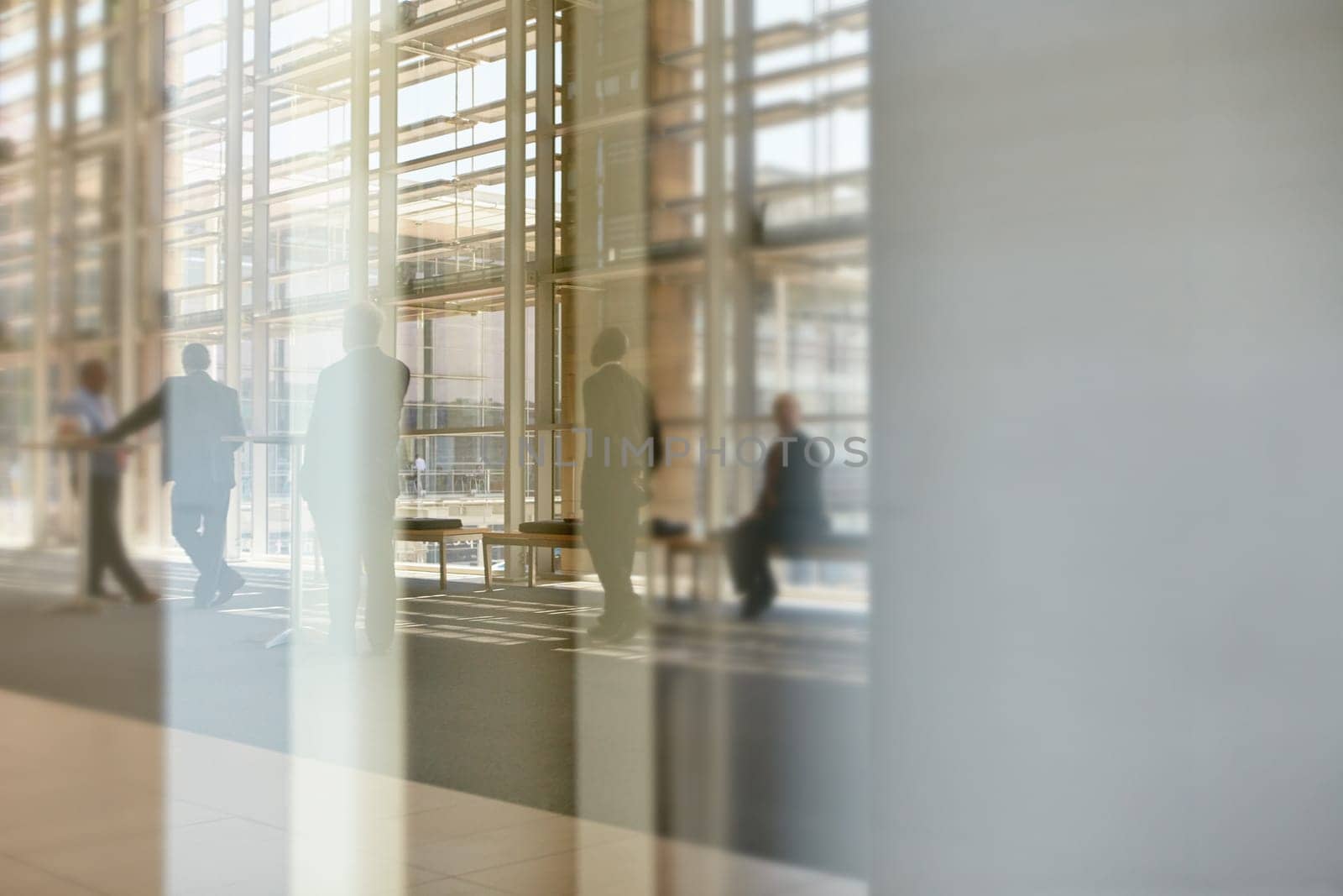 Abstract images of real businesspeople in motion through glass in a busy conference centre
