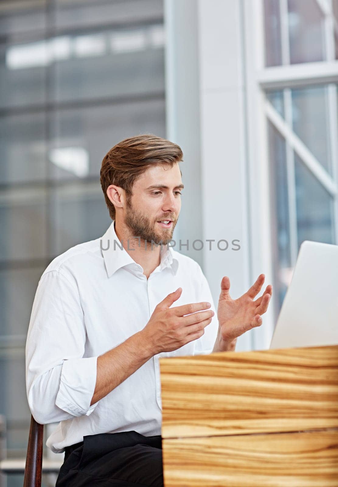 Young businessman engaged in a conversation on his laptop in a corporate setting