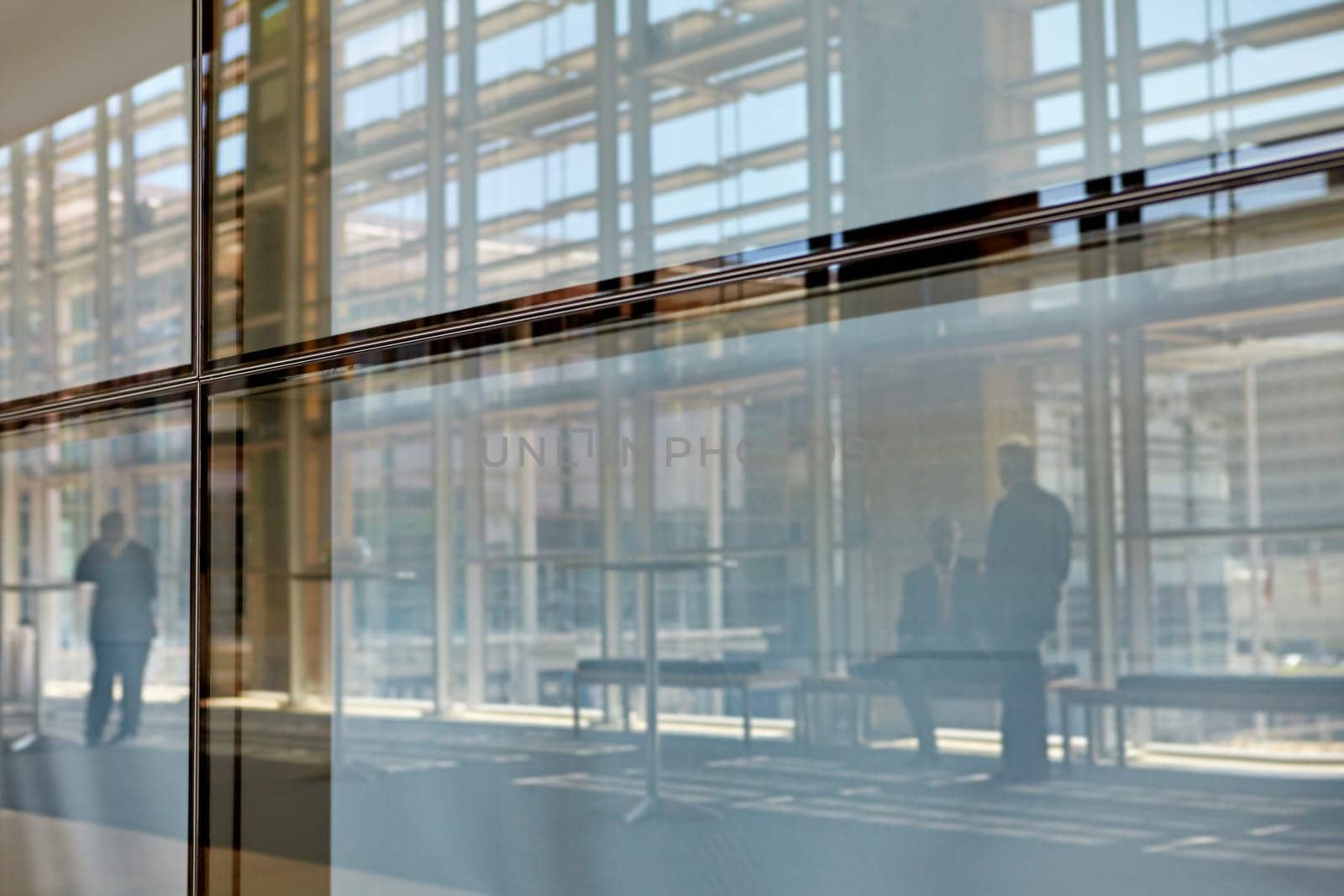 Abstract images of real businesspeople in motion through glass in a busy conference centre