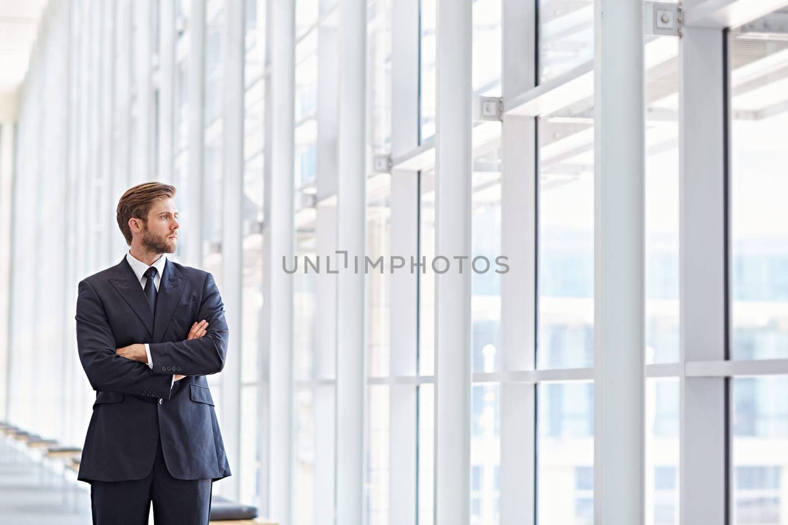 Corporate executive in a modern architectural setting looking confidently out of high rise windows
