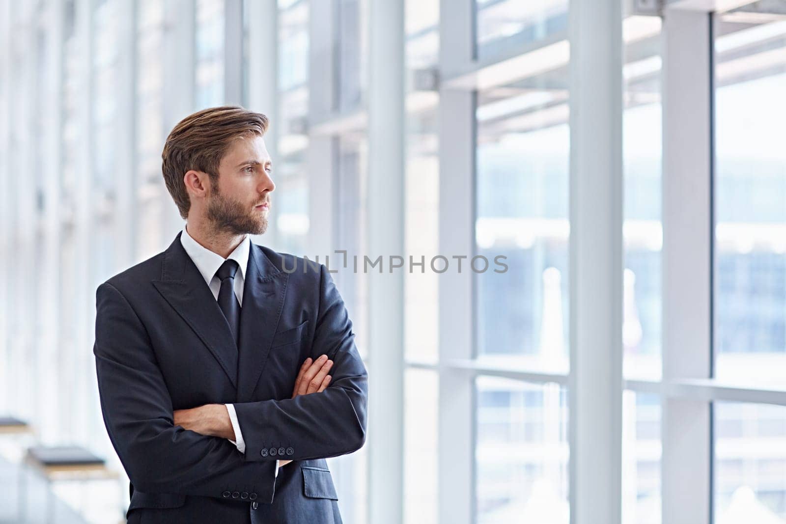 Corporate executive in a modern architectural setting looking confidently out of high rise windows