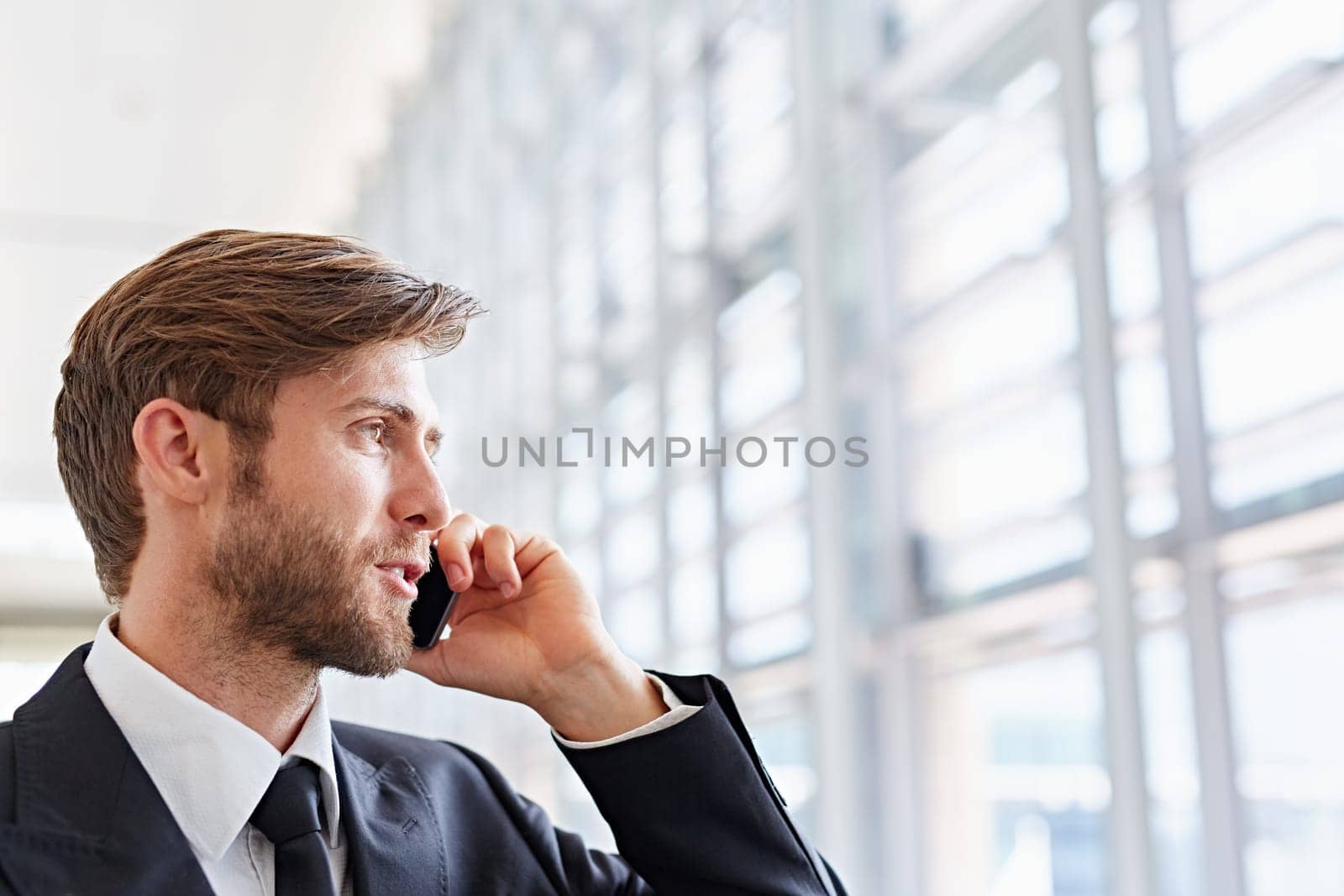 Closeup of a corporate executive looking away confidently while talking on his mobile phone