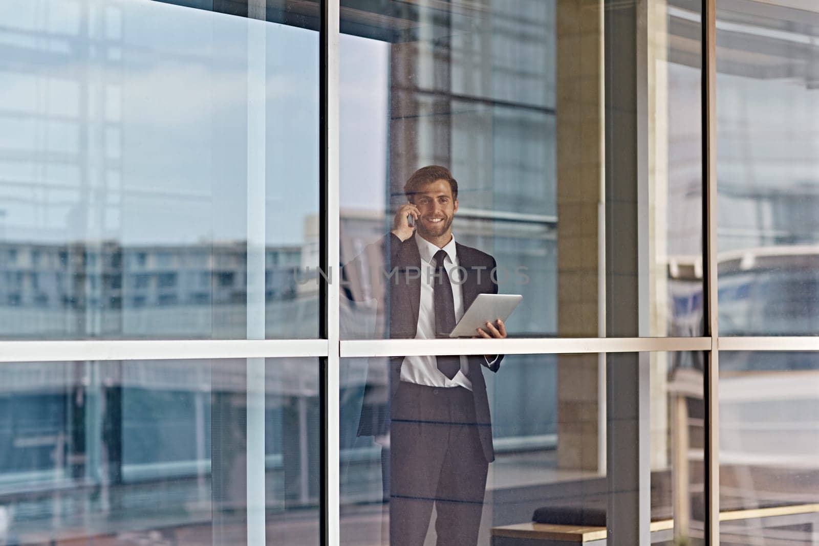 A businessman looking out the window while holding a tablet