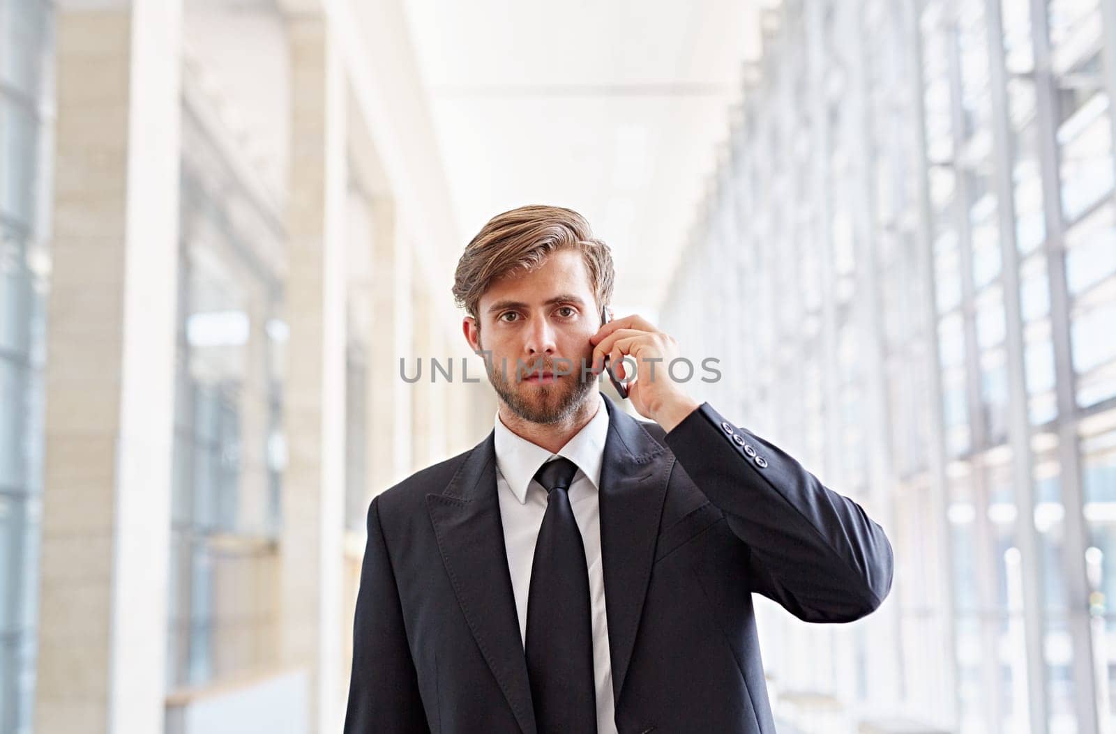 Portrait of a corporate executive looking seriously at the camera while listening on his phone